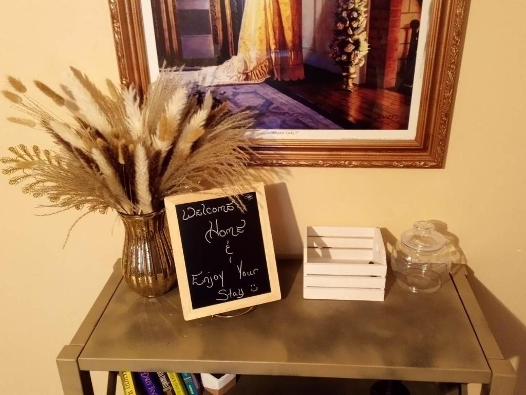 uma mesa com um sinal de quadro negro numa mesa com um vaso em Country Cottage em Kathleen