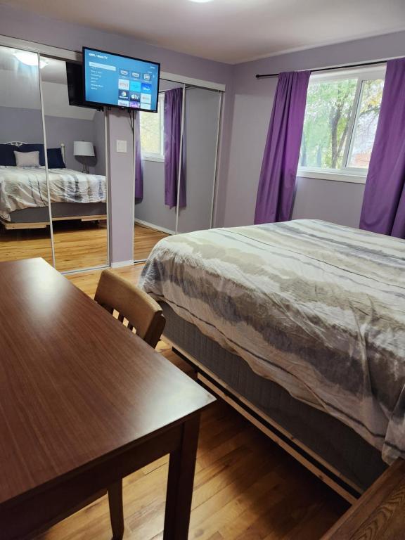 a bedroom with a bed and a table and a tv at Winnipeg Place to Stay in Winnipeg