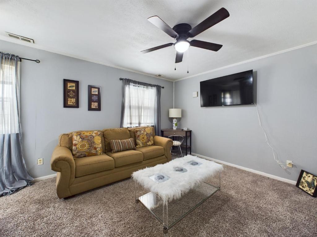 uma sala de estar com um sofá e uma ventoinha de tecto em Pine Forest Zen Cottage - 10 min to Fort Bragg em Fayetteville