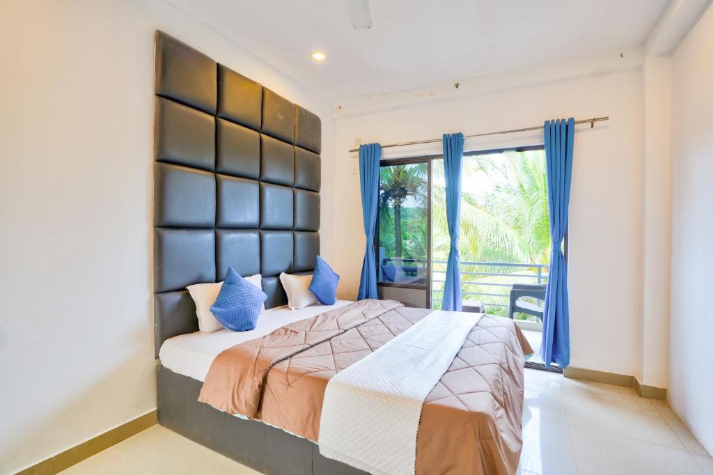 a bedroom with a bed with blue curtains and a window at GOA Down D Vilage Prime in Candolim