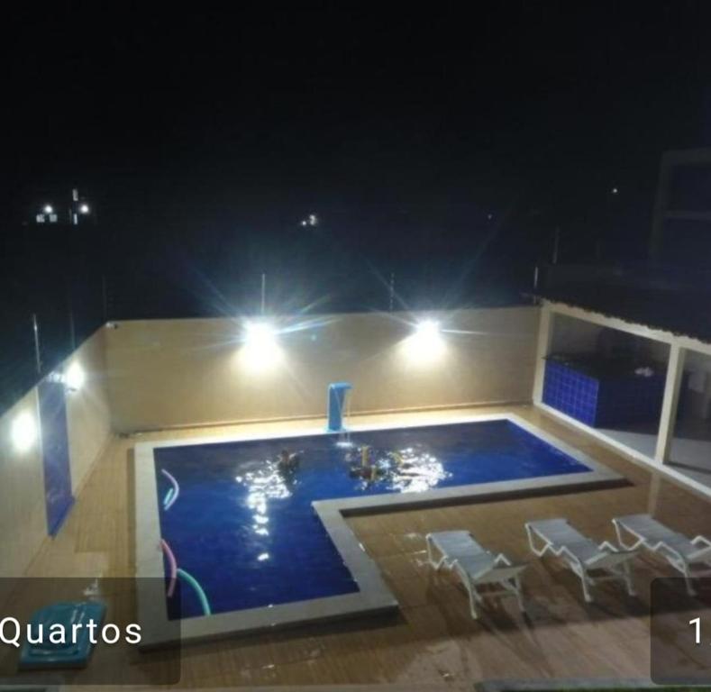 a swimming pool at night with chairs around it at DUNAS RESIDENCE CASA 02 in Santo Amaro