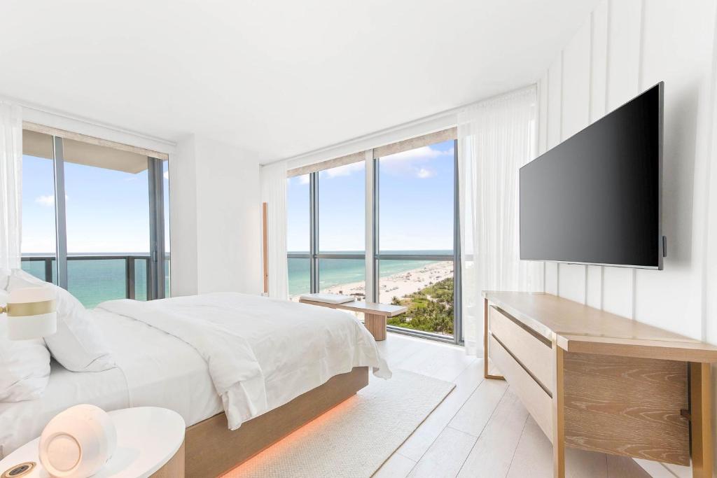 a white bedroom with a bed and a flat screen tv at W South Beach in Miami Beach