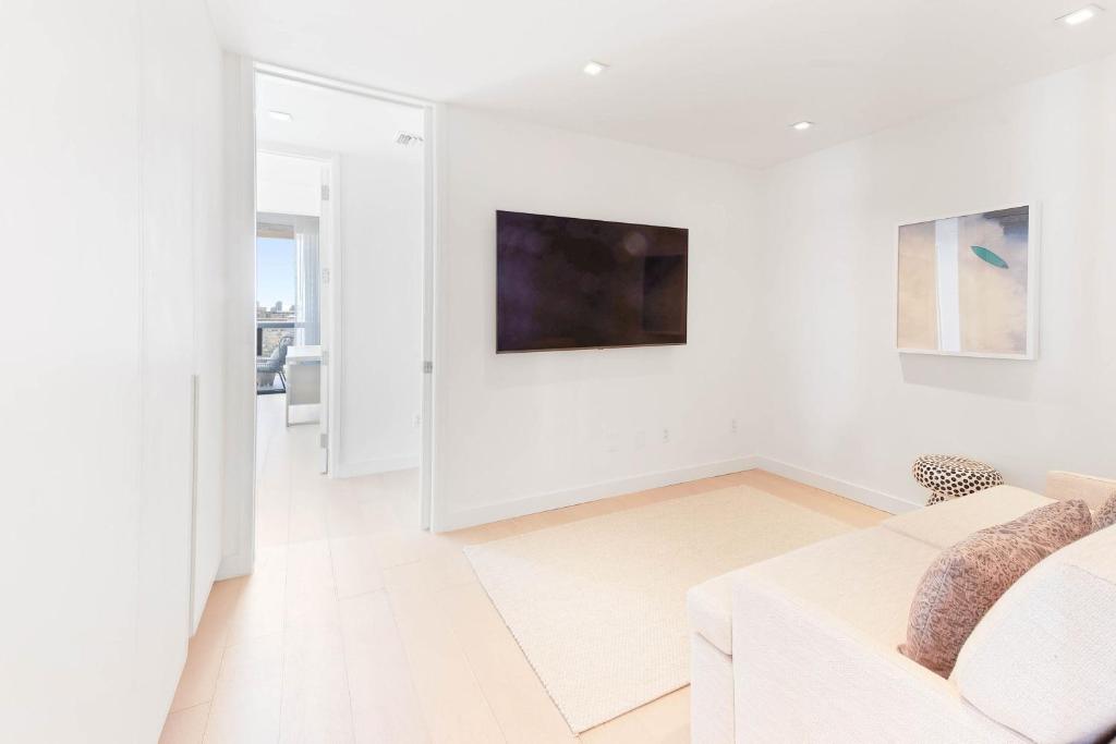 a white living room with a white couch and a tv at W South Beach in Miami Beach