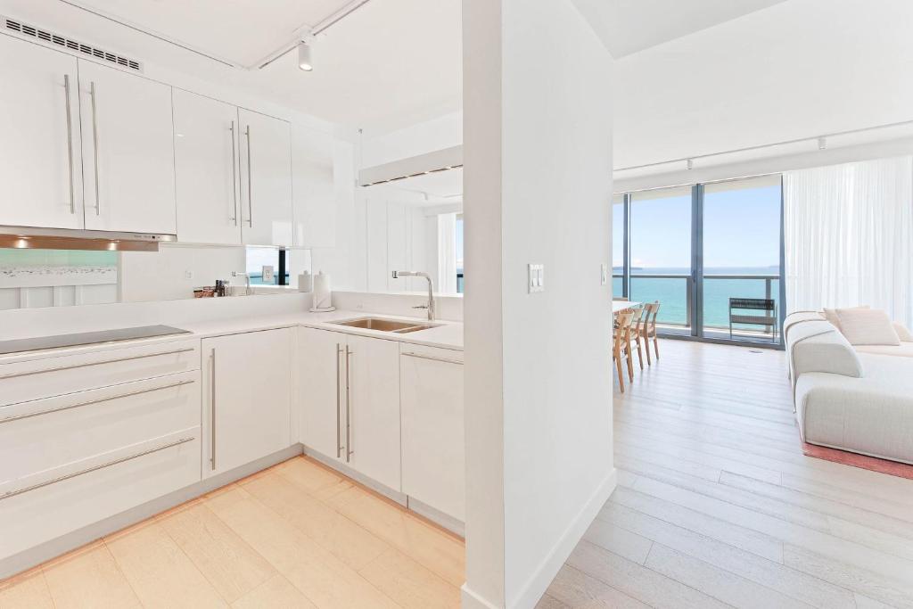 a white kitchen with white cabinets and a living room at W South Beach in Miami Beach