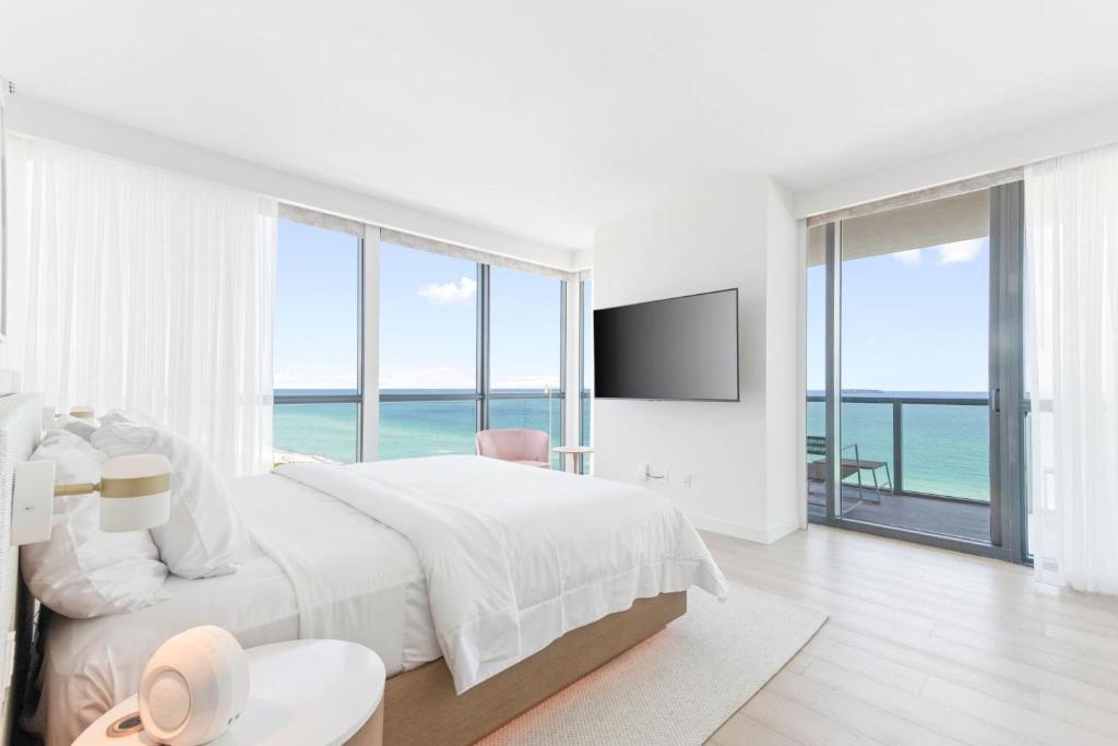 a white bedroom with a large bed with a view of the ocean at W South Beach in Miami Beach