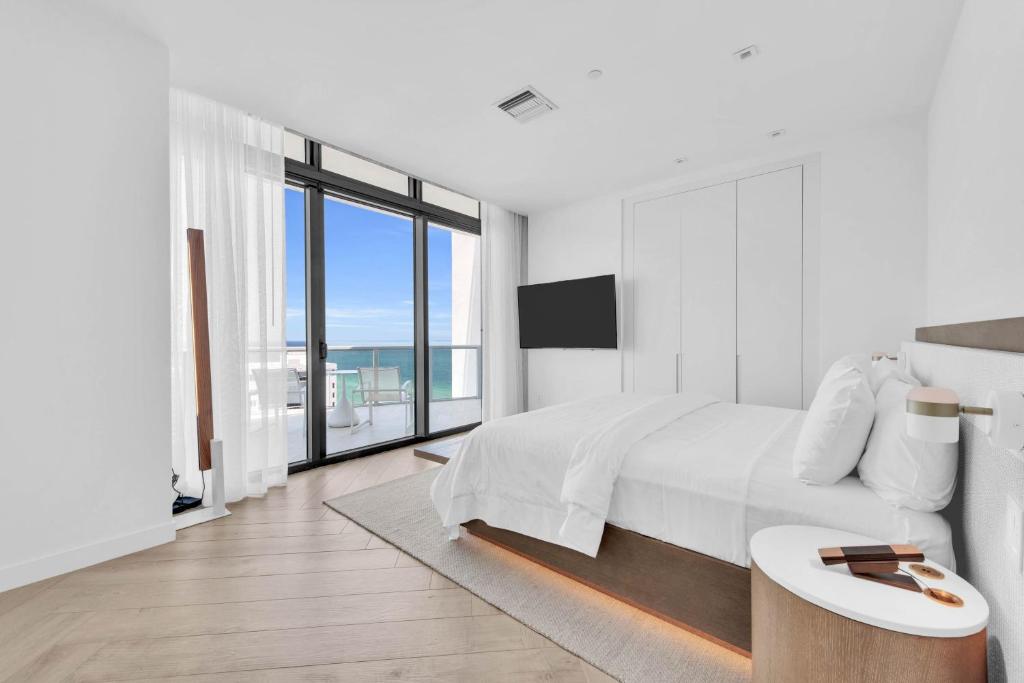 a white bedroom with a bed and a large window at W South Beach in Miami Beach