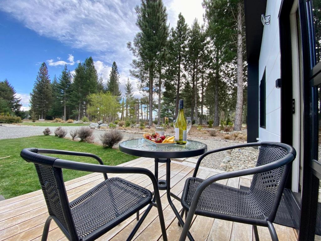 einen Tisch und zwei Stühle auf einer Veranda mit einer Flasche Wein in der Unterkunft Alpine Views and River Tracks in Twizel