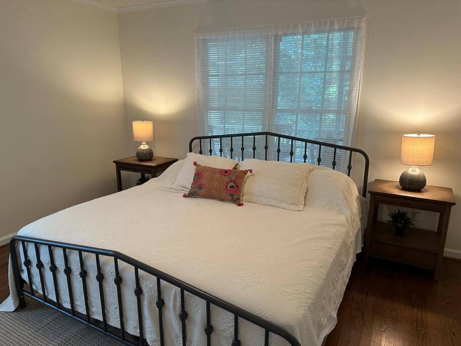 a bedroom with a bed with two night stands and a window at The Mirror Lake Suite in Fayetteville