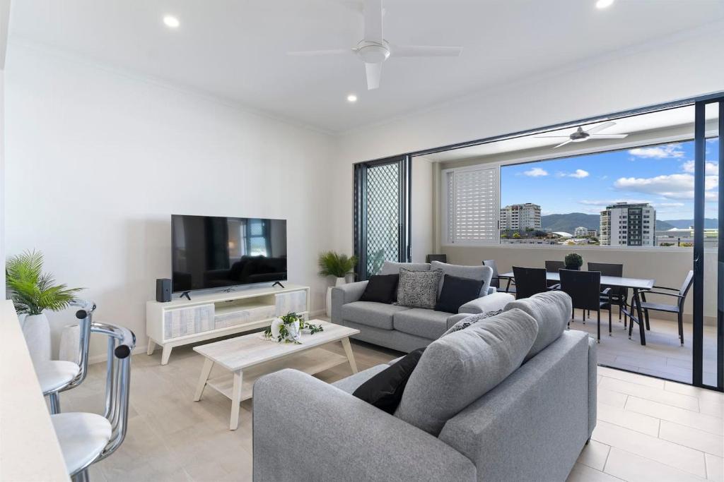 uma sala de estar com um sofá, uma televisão e uma mesa em Mountain Air and Modern Flair 'Your Cairns Getaway' em Cairns