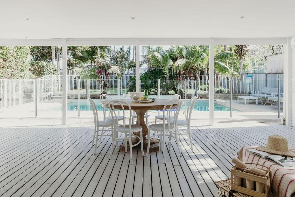 une terrasse en bois avec une table et des chaises ainsi qu'une piscine dans l'établissement The Beach House, 25 Tomaree Road - fantastic house with pool, linen, à Shoal Bay