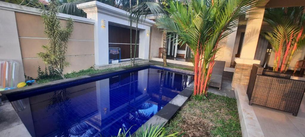 a swimming pool in front of a house with a palm tree at Rama Bharata Villa in Ubud