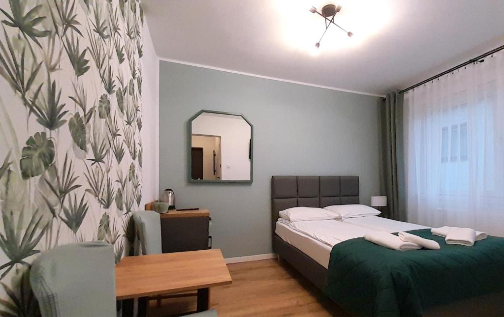um pequeno quarto com uma cama e um espelho em Trzy Kolory em Polanica-Zdrój