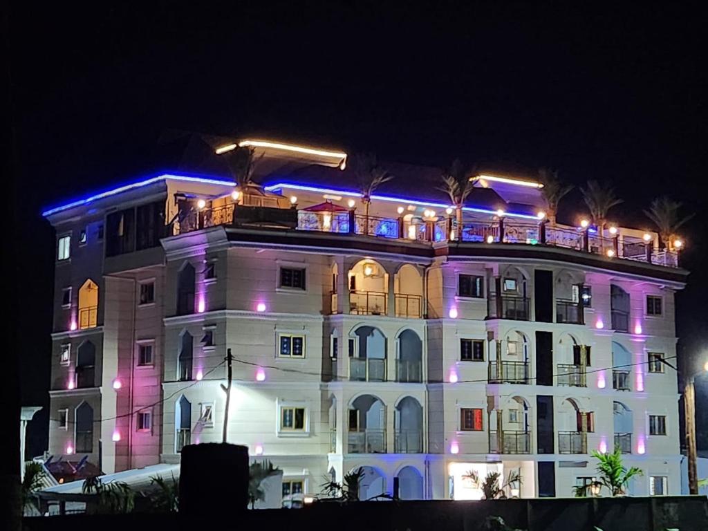 Buea的住宿－Rovie Estates，一座白色的大建筑,上面有紫色的灯