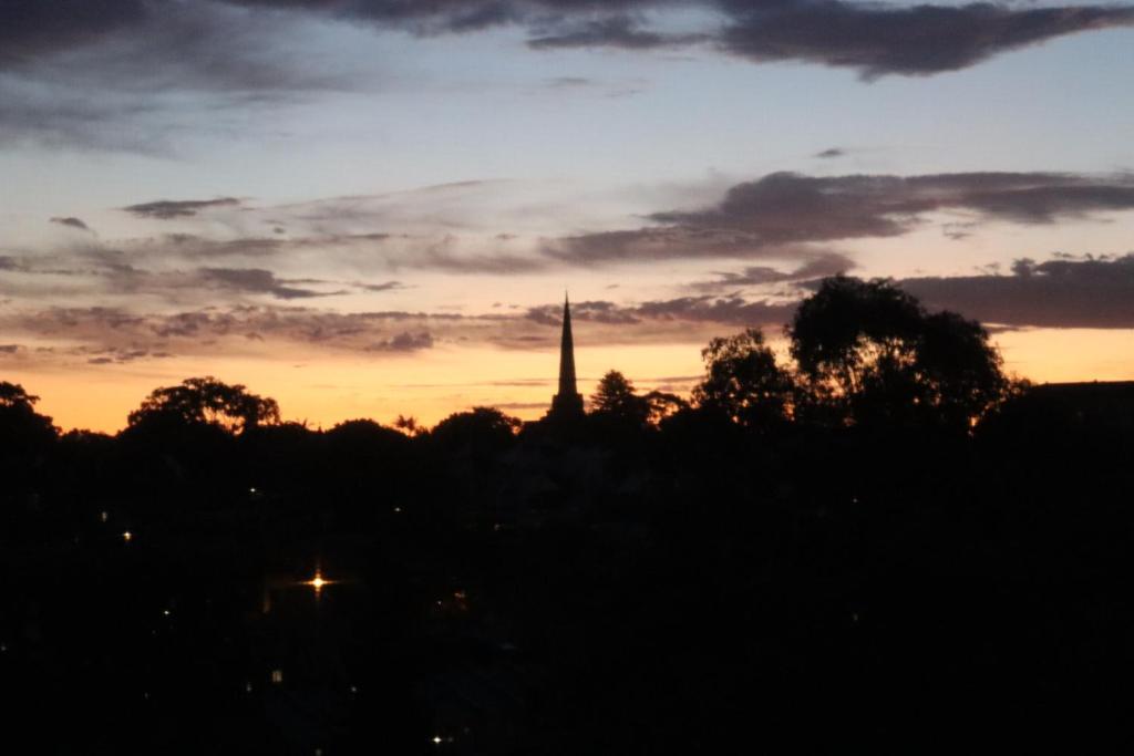 un coucher de soleil avec une cloche d'église au loin dans l'établissement Wandering a private room with shared bathroom, à Sydney