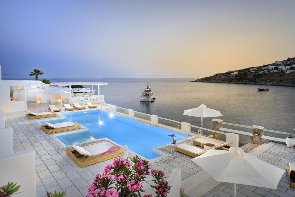 
a beach area with a pool, chairs and tables at Nissaki Boutique Hotel in Platis Yialos Mykonos
