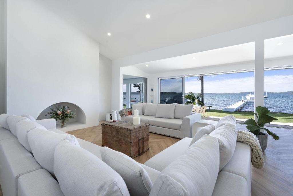 a living room with white furniture and the ocean at Boat Harbour Haven in Bonnells Bay