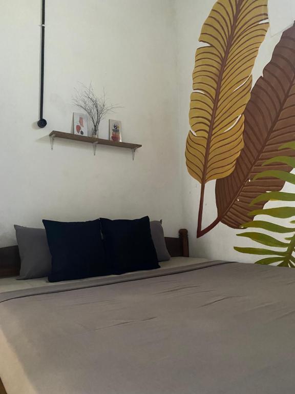 - une chambre avec un lit orné d'une grande fresque murale représentant les feuilles dans l'établissement Banana Homestay, à Banyuwangi