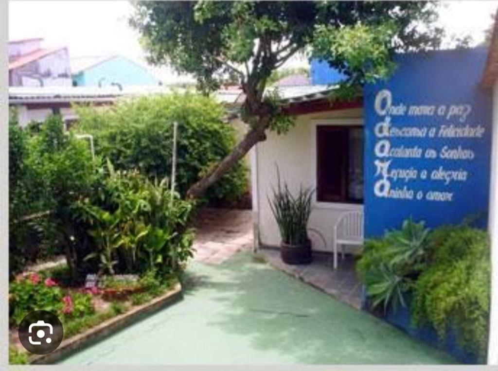 a sign in front of a house with a garden at POUSADA ODARA à Beira Mar in Saquarema