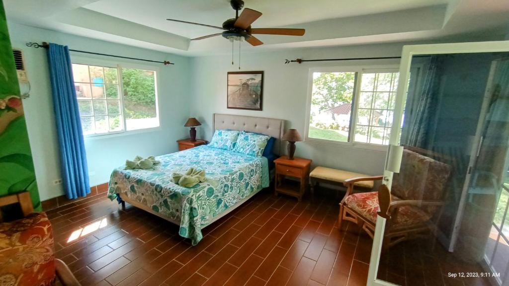 a bedroom with a bed and a chair and windows at Villas at Gone Fishing Panamá Resort in Boca Chica