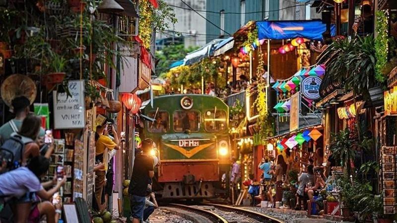 a train traveling down the tracks in a crowd of people at Homestay Torna A Casa không thang máy in Hanoi