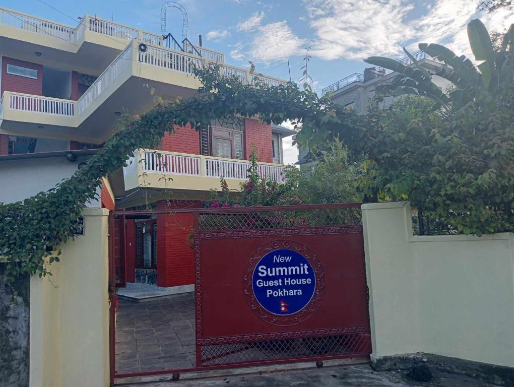 un edificio con una puerta roja con un cartel. en New Summit Guest House, en Pokhara