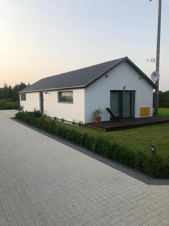 Biały dom z podjazdem przed nim w obiekcie Przytulny domek z ogrodem, parkingiem oraz innymi udogodnieniami w mieście Malbork