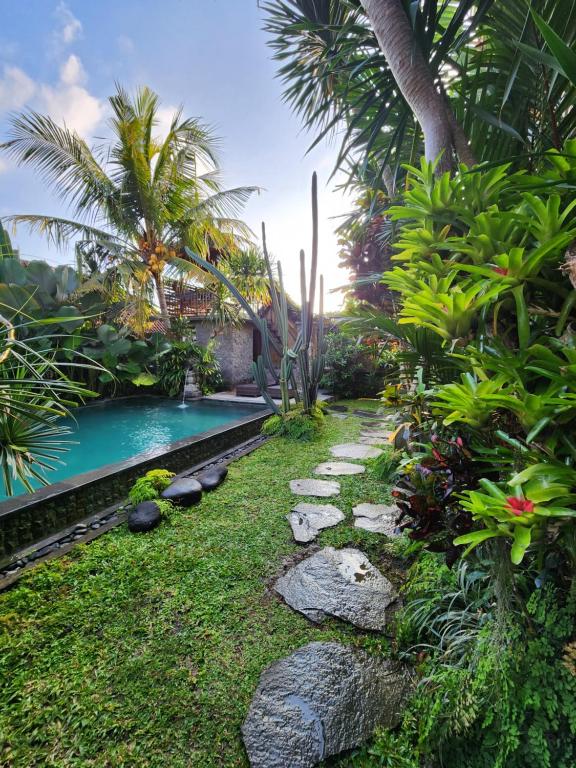 a garden with a swimming pool and palm trees at BUDA AMITABA in Ubud