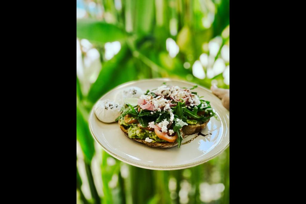 a person holding a plate with a plate of food at Rascals Hotel - Adults Only in Kuta Lombok