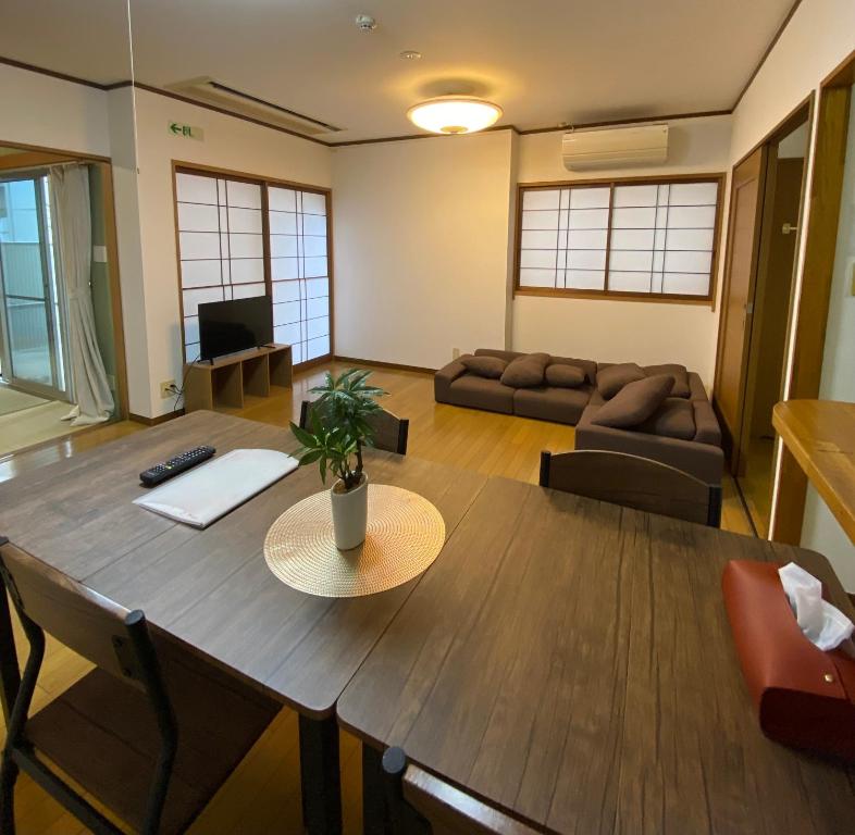 ein Wohnzimmer mit einem Tisch und einem Sofa in der Unterkunft Guest House Flora Otemachi/フローラ大手町 in Hiroshima