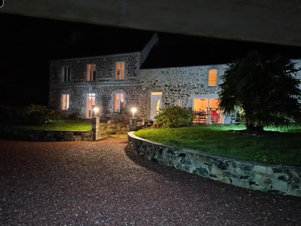 una casa de piedra por la noche con sus luces encendidas en Chambre d'hôte la Coquierrerie, en Sottevast