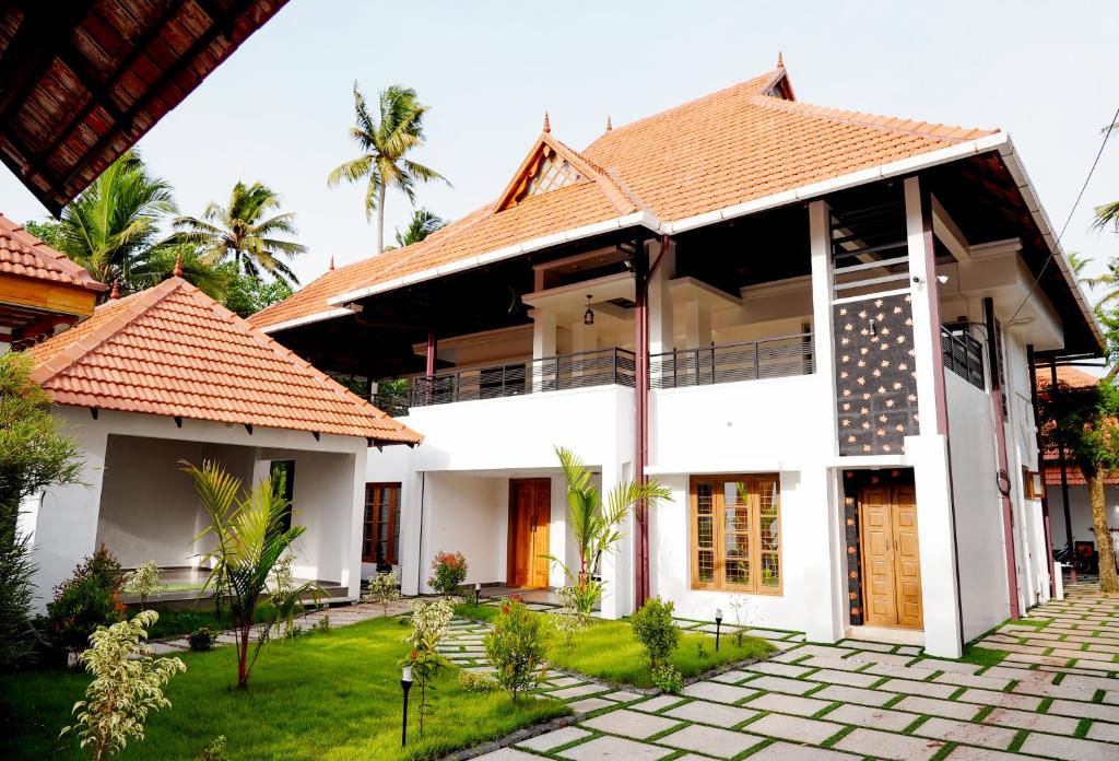 une maison blanche avec un toit rouge dans l'établissement Kalloos Island Backwater Resort, à Kollam