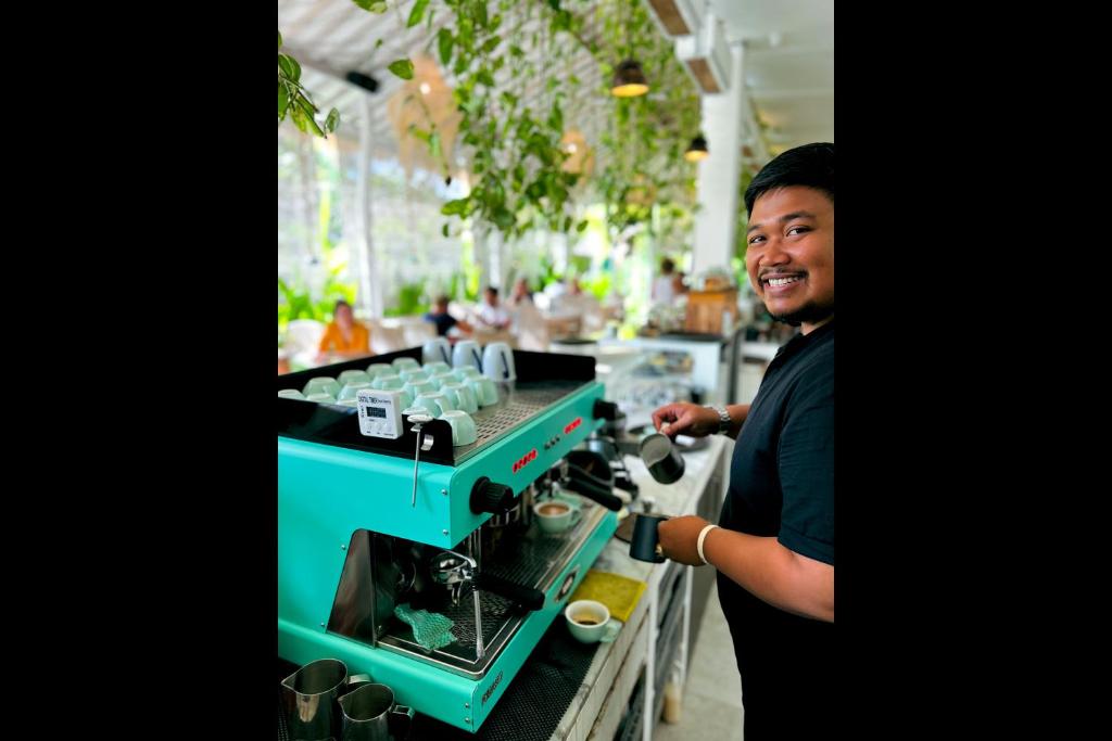 a man is standing next to a coffee machine at Rascals Hotel - Adults Only in Kuta Lombok