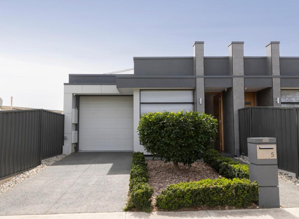 a house with a garage and a fence at Cozy Getaway, King Bed with TV, NBN, Netflix, Nespresso in Christies Beach
