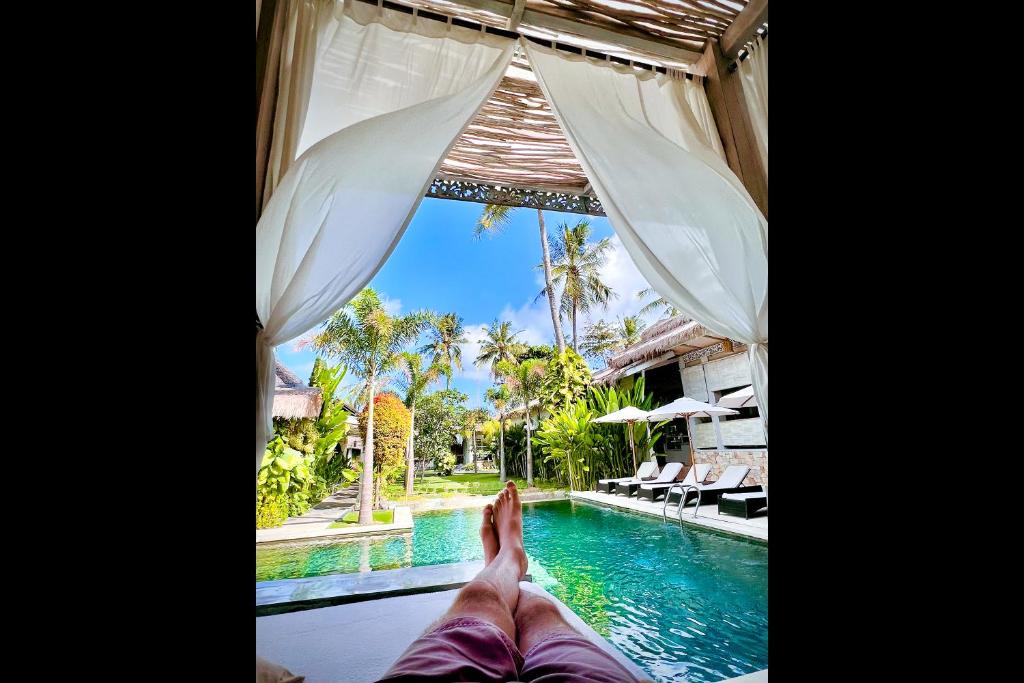 a person laying in a hammock next to a swimming pool at Rascals Hotel - Adults Only in Kuta Lombok