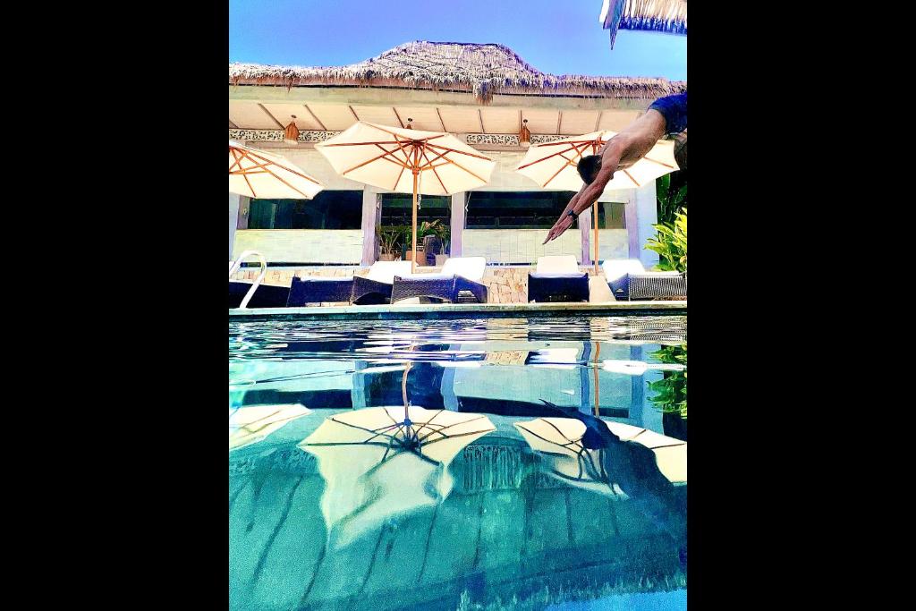 a person jumping into a swimming pool at Rascals Hotel - Adults Only in Kuta Lombok