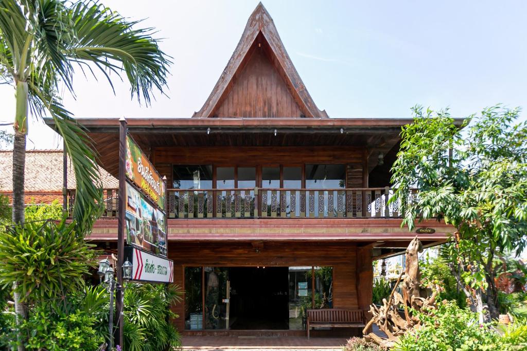 een houten huis met een balkon en palmbomen bij Deeden Pattaya Resort in Pattaya South