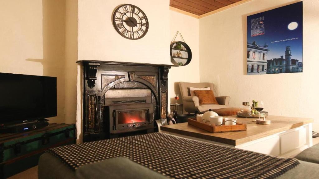 sala de estar con chimenea y reloj en la pared en Gladstone House, en Beechworth