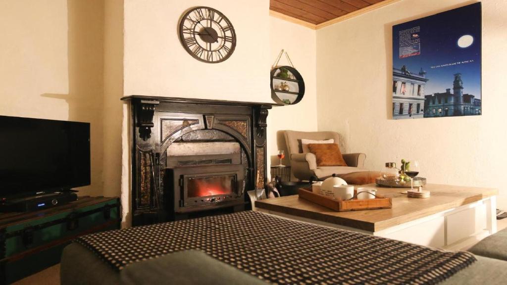 a living room with a fireplace and a clock on the wall at Gladstone House in Beechworth