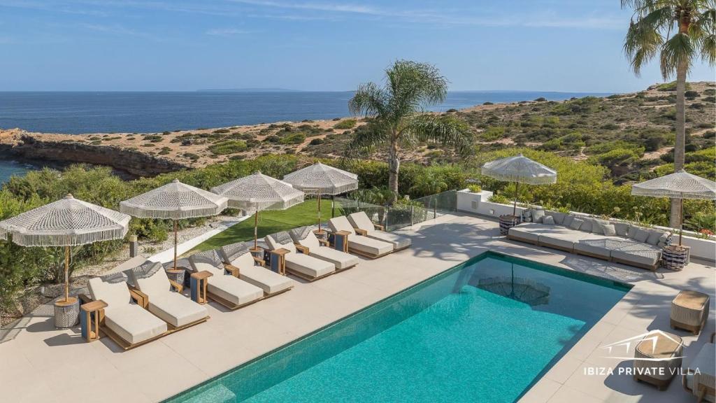 une image d'une piscine avec des chaises et des parasols dans l'établissement Villa Wave, à Ibiza