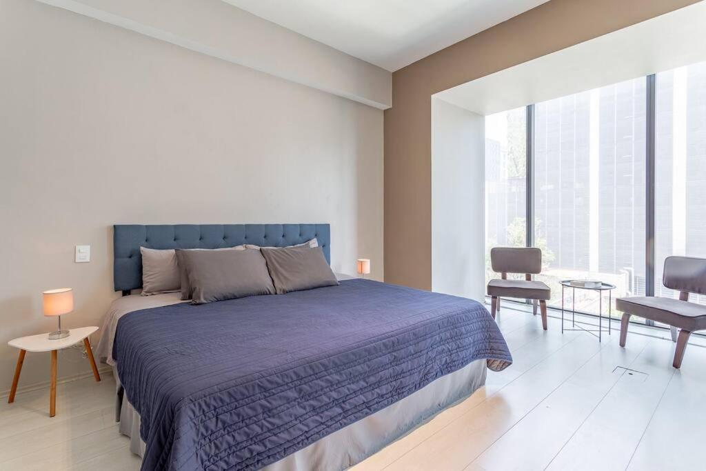 a bedroom with a blue bed and a large window at Moderno Departamento en Reforma 284 in Mexico City