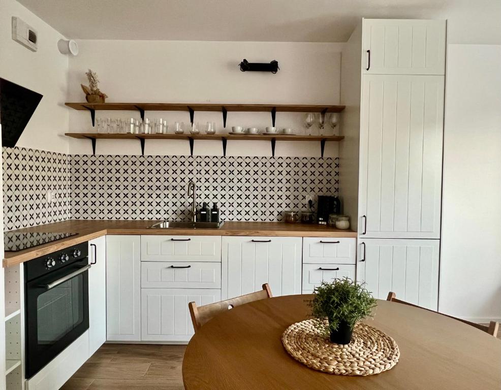 a kitchen with white cabinets and a wooden table at Apartament Przytulny 3, self check in, parking in Rzeszów