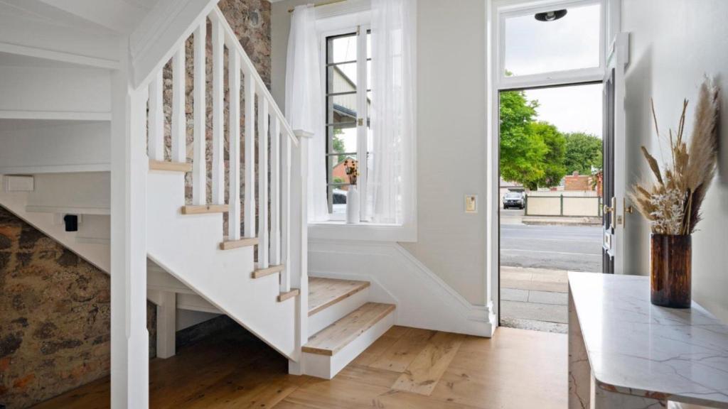 a white staircase in a living room with a table at 1858 - The Prospect in Beechworth