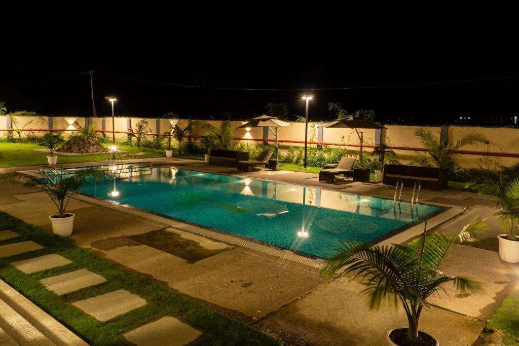 a swimming pool in a yard at night at Palm Resorts in Tinsukia