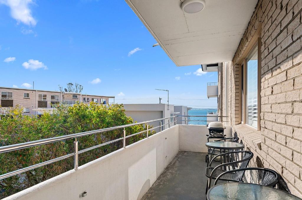 a balcony with tables and chairs and a view of the ocean at Del Rae Unit 15 25 Shoal Bay Road in Shoal Bay