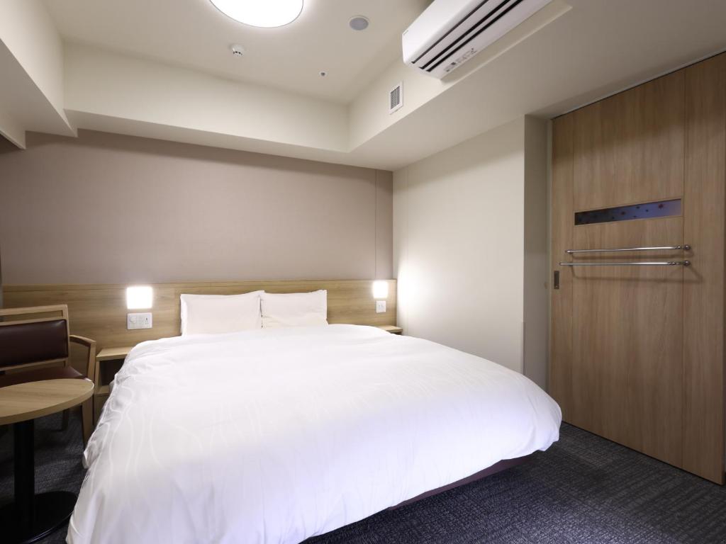 Postel nebo postele na pokoji v ubytování Dormy Inn Hiroshima Annex