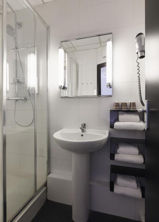 a white bathroom with a sink and a shower at Hôtel de Noailles in Lyon