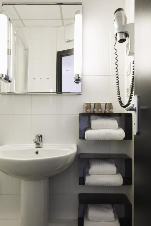 a white bathroom with a sink and a mirror at Hôtel de Noailles in Lyon