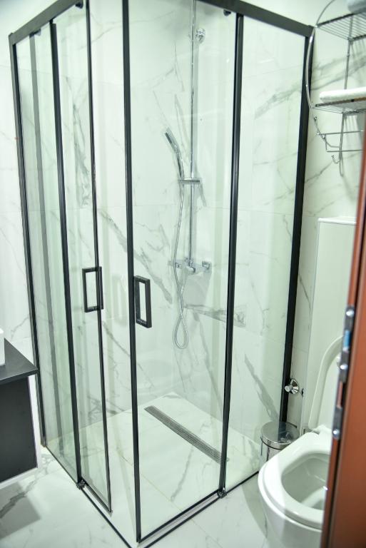 a bathroom with a glass shower with a toilet at Apartmani COLOSSEUM in Bratunac