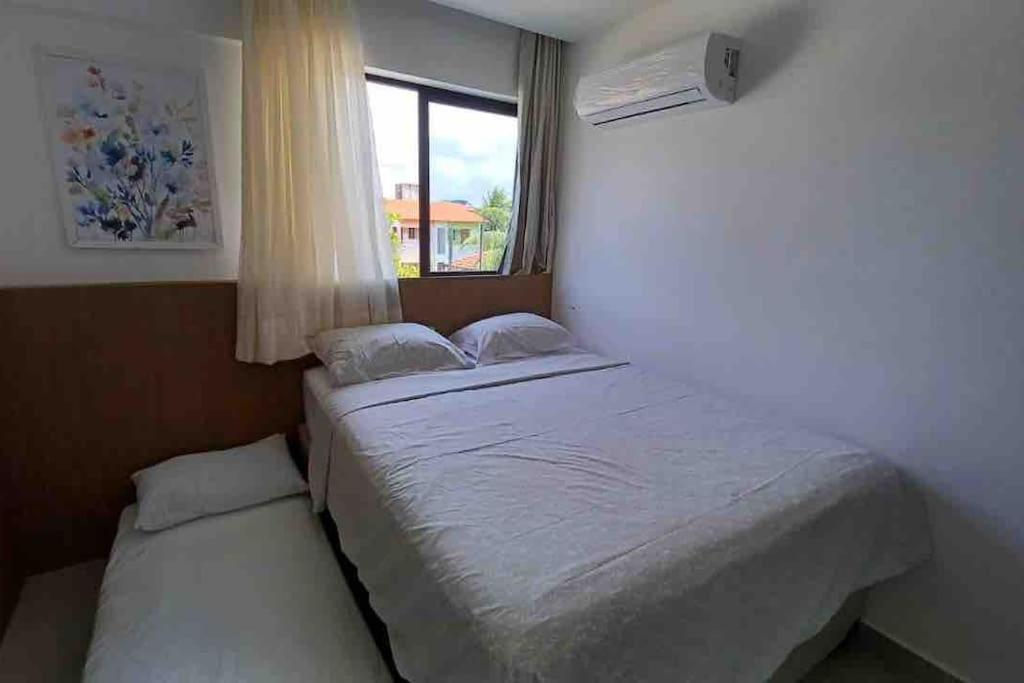 a small bedroom with a bed and a window at Residencial Taormina - apartamento à beira-mar novinho! in Tamandaré