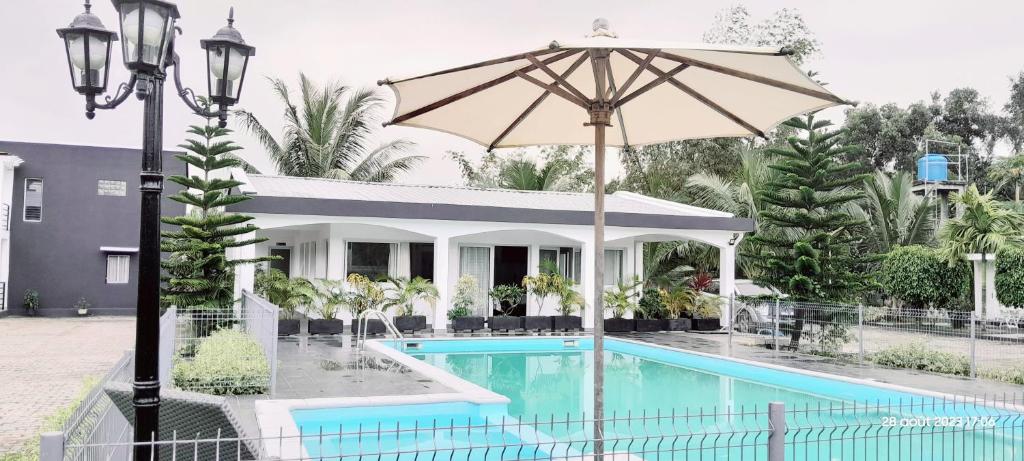 a swimming pool with an umbrella next to a house at EDENA Village in Foulpointe